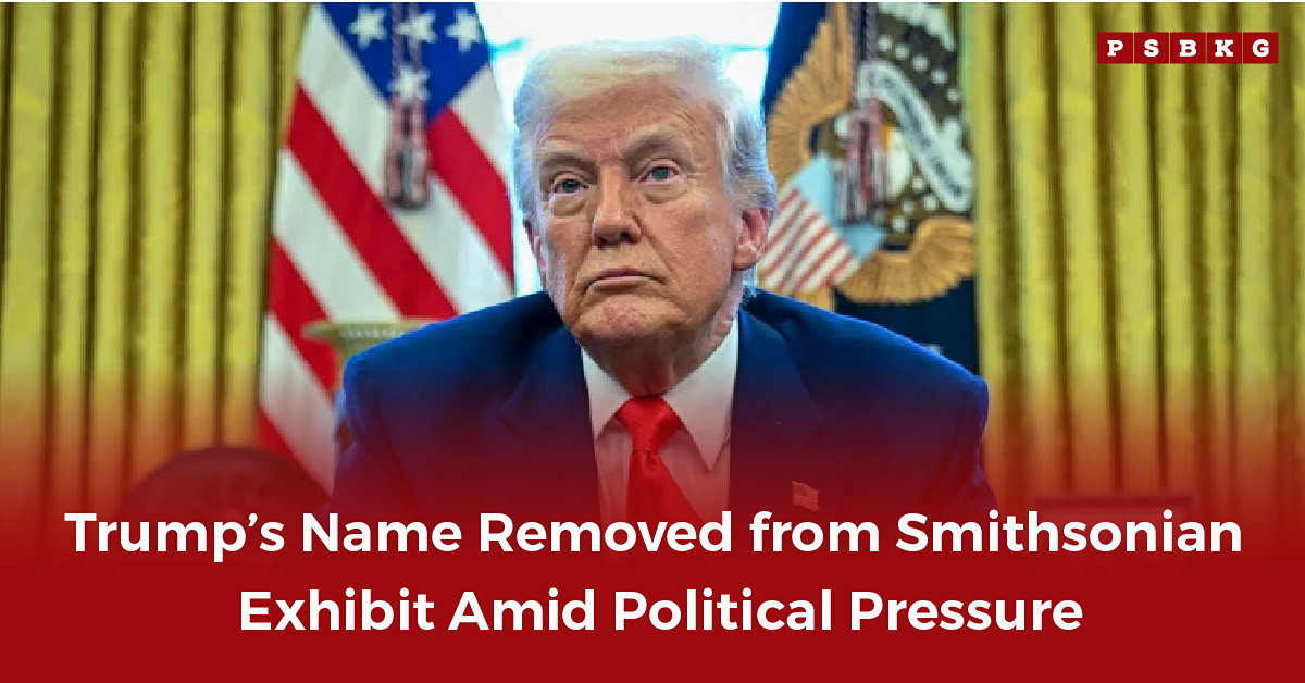 An official setting with a man in a suit addressing the media, standing before national flags and an official seal, discussing the Smithsonian exhibit decision where Trump’s name removed.