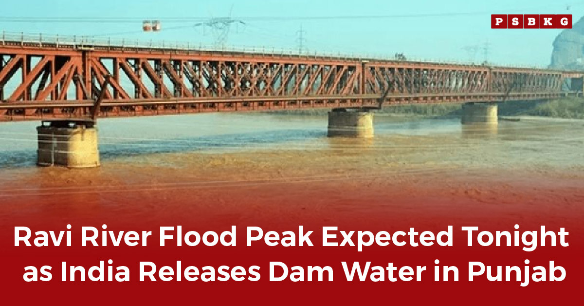 A metal bridge over a swollen muddy river under a clear sky, warning of potential Ravi River flood after dam water release.