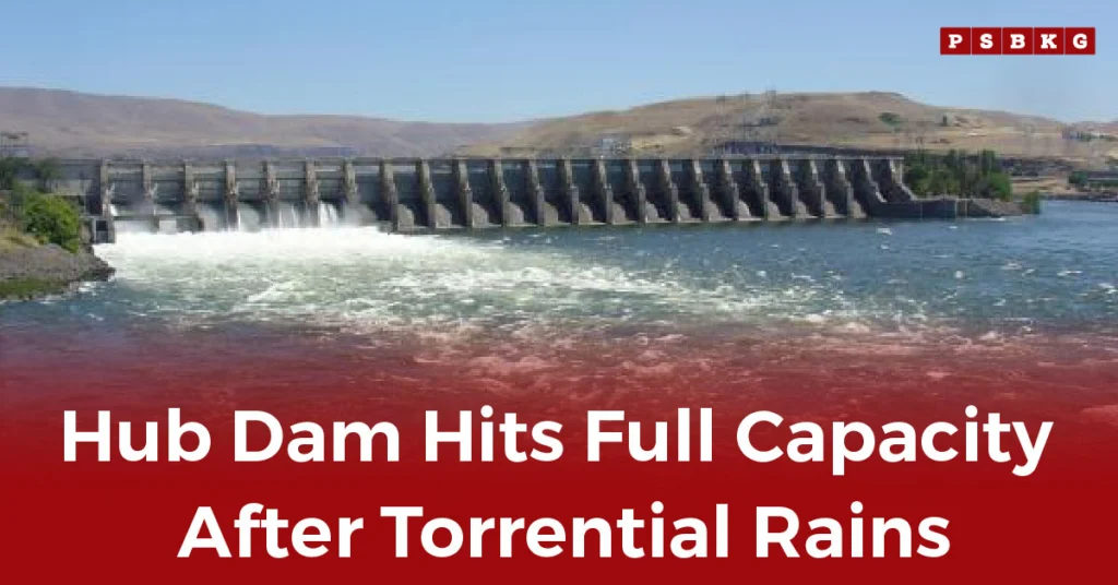 Hub Dam full capacity The dam overflowing with water after torrential rains, showcasing its maximum level against a scenic hill backdrop.