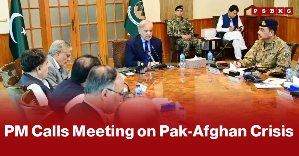 A group of officials, including a man in a blue suit speaking at a table, discuss the Pak-Afghan crisis as PM calls meeting with senior military and intelligence personnel. The tone is serious.