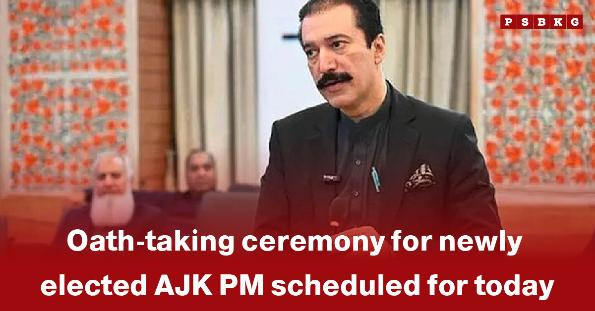 A speaker in formal attire stands before a backdrop decorated with floral patterns, announcing the ceremony where the newly elected AJK Prime Minister will take oath capturing the AJK PM oath-taking event in a natural way.