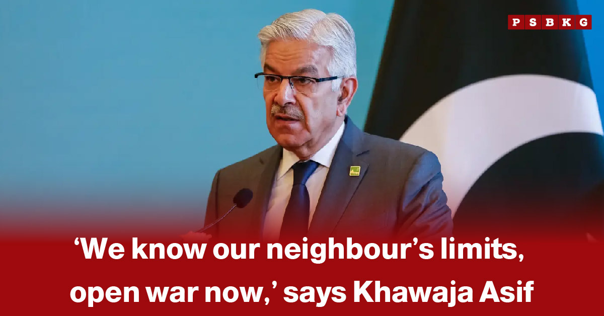 Khawaja Asif open war statement: A man speaks at a podium discussing tensions with a neighboring country, with a blurred face and a large national flag in the background.