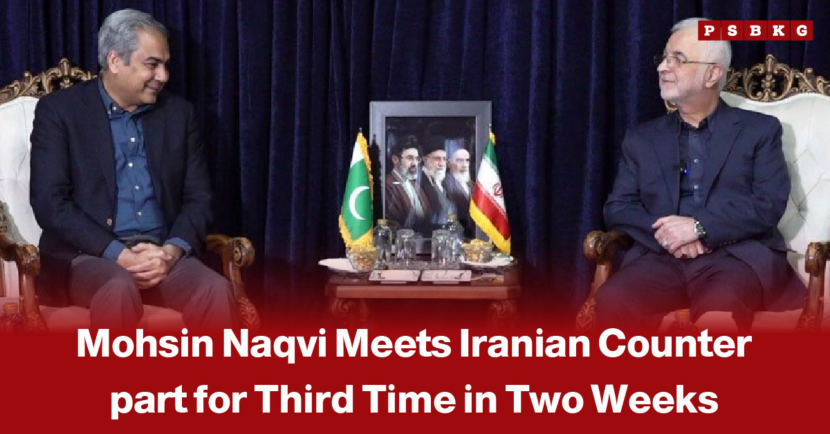 Image of two officials in suits seated on ornate chairs during a diplomatic meeting, with Pakistan and Iran flags displayed on a table between them against a deep blue curtain backdrop, highlighting Mohsin Naqvi’s third meeting with an Iranian counterpart in two weeks.