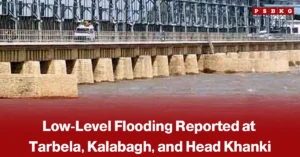 Large dam with water flowing through its spillways and vehicles crossing the bridge above, accompanied by a news-style headline about low-level flooding reported at Tarbela, Kalabagh, and Head Khanki.